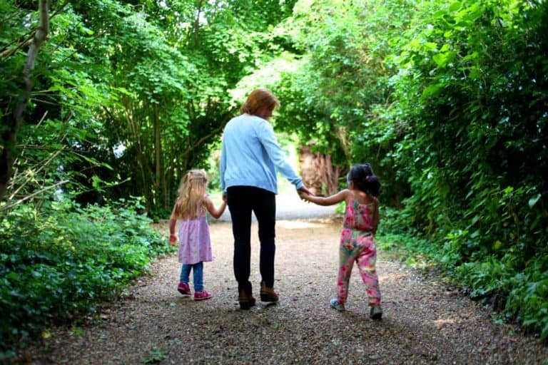 An adult and two children walking down Millington Road Nursery School leafy lane entrance