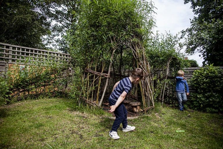 Two children playing outside the wooden tipi