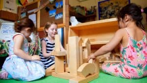 Three children play with wooden building blocks