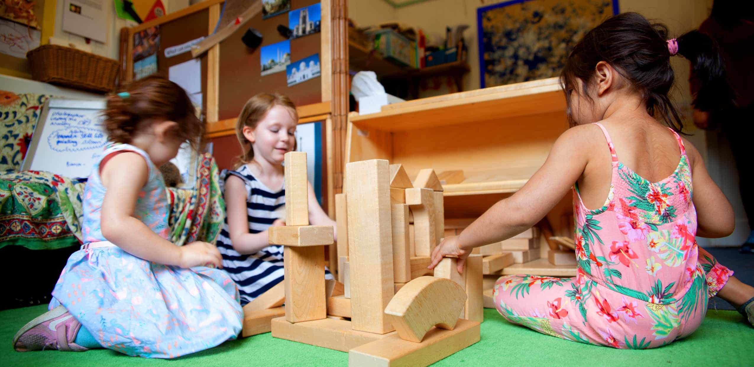 Three children play with wooden building blocks