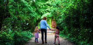 An adult with two children walking down Millington Road Nursery School leafy lane entrance
